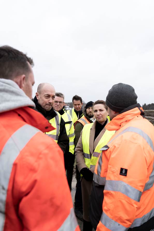 Statsminister Mette Frederiksen og miljøminister Magnus Heunicke lytter til arbejdere fortælle om oprydningsarbejdet ved jordskredet