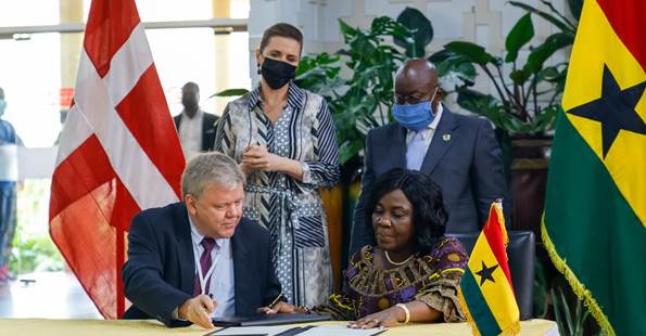 Statsminister Mette Frederiksen og Ghanas præsident i baggrunden mens ambassadørerne for Danmark og Ghana underskriver hensigtserklæring om at nå SDG6-målene.