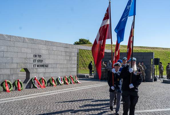 Veteraner bærer Dannebrog og FN-flaget ved Monument for Danmarks Internationale Indsats