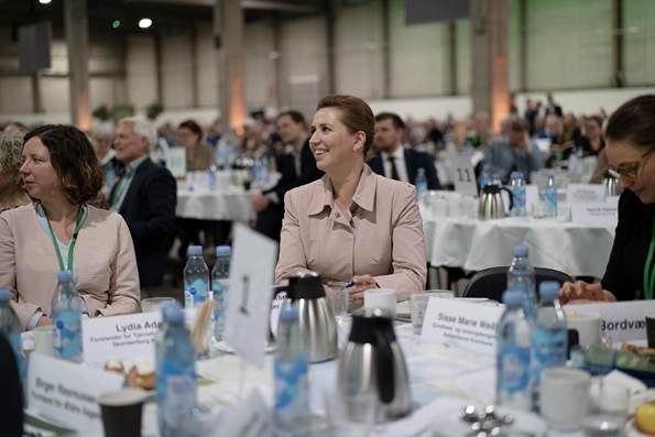 Statsminister Mette Frederiksen smiler ved sit bord