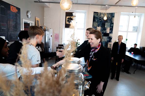 Statsminister Mette Frederiksen og beskæftigelsesminister Ane Halsboe-Jørgensen hilser på unge frivillige der arbejder i caféen på Unge-værestedet KBH+
