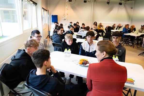 Statsminister Mette Frederiksen taler med seks elever ved et bord