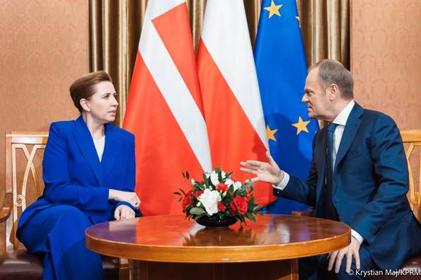 Statsminister Mette Frederiksen sidder ned ved et bord og samtaler med Polens Premierminister Donald Tusk